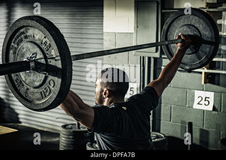 Young man holding up barbell in gymnasium Stock Photo