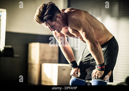 Young man bending forward with exhaustion in gymnasium Stock Photo