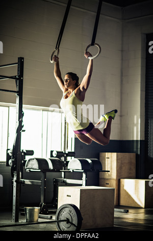 Young woman training on rings in gymnasium Stock Photo
