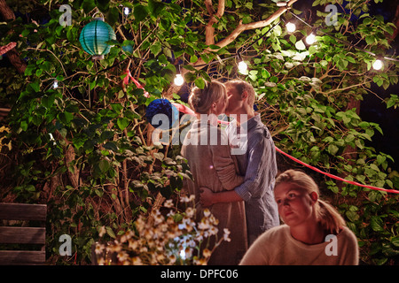 Young couple embracing at garden party at night Stock Photo