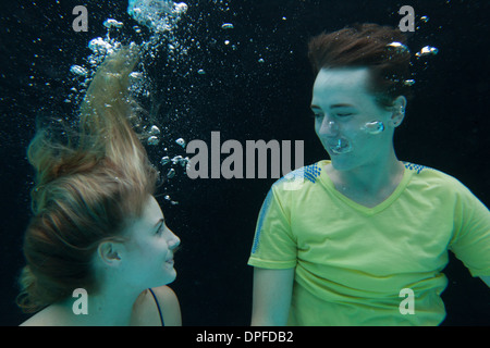 Young couple fully clothed floating underwater Stock Photo