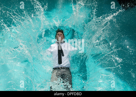 Young man in clothes falling into swimming pool Stock Photo