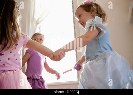 Three young girls in party dress holding hands and dancing Stock Photo