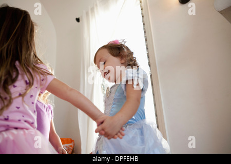 Three young girls in party dress dancing in circle Stock Photo