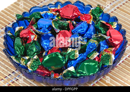 Chocolate candy with wrappers of different colors in the glass blue dish Stock Photo