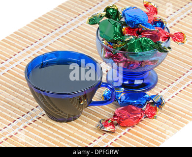 Cup of black tea and chocolates in a bowl of blue glass Stock Photo