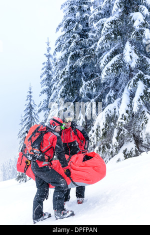 Ski patrol carry injured person skier in rescue stretcher snow Stock Photo