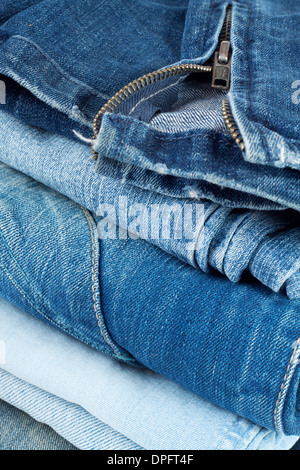 Stack of jeans in different colors with a snake on top Stock Photo