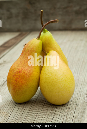 Three ripe pears with cuttings on a wooden background Stock Photo