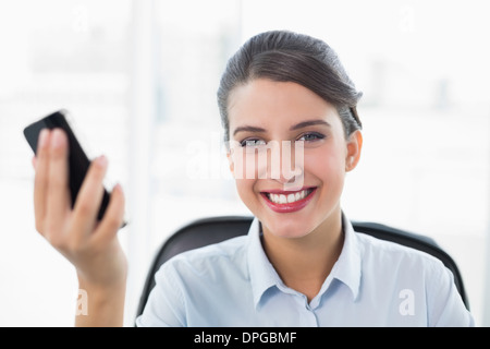 Content classy brown haired businesswoman holding a mobile phone Stock Photo