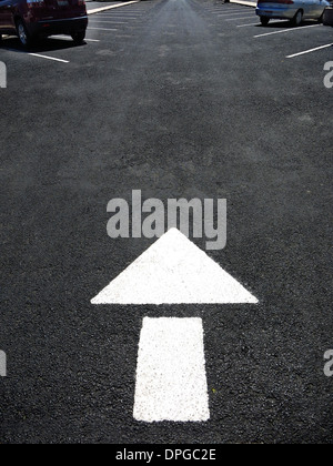 White arrow painted on road for cars to follow directions Stock Photo