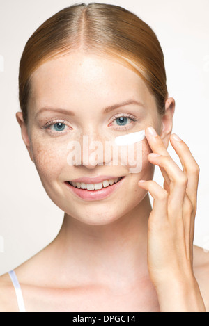 Young woman applying moisturizer under eye Stock Photo