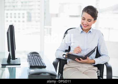 Content classy brown haired businesswoman checking her agenda Stock Photo