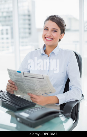 Content classy brown haired businesswoman reading a newspaper Stock Photo