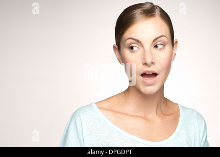 Young woman looking away with mouth open in surprise, portrait Stock Photo