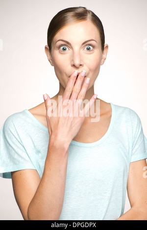 Woman covering mouth in surprise, portrait Stock Photo