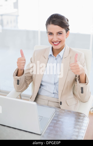 Content smart brown haired businesswoman giving thumbs up Stock Photo