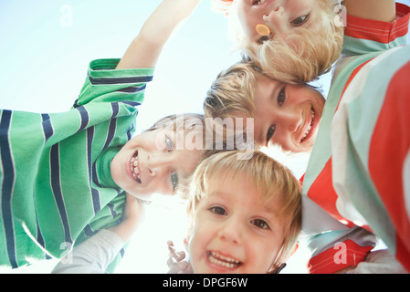 Boys huddling, smiling down at camera Stock Photo