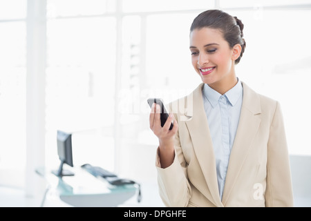 Content smart brown haired businesswoman looking at her mobile phone Stock Photo