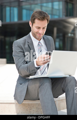 Businessman multitasking while working outdoors Stock Photo