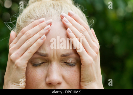 Woman holding head with distressed expression Stock Photo