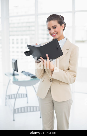 Content smart brown haired businesswoman filling an agenda Stock Photo