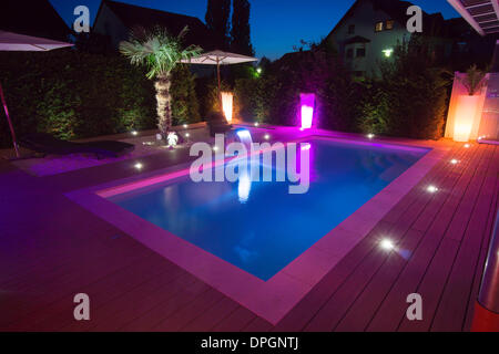 Private garden with pool and terrace and palm with show lighting at night in summer, Germany, Europe - August 2013.