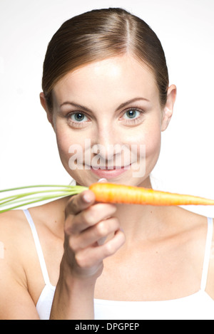 Young woman balancing carrot on hand, portrait Stock Photo