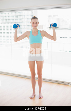 Sporty smiling woman holding up dumbbells Stock Photo
