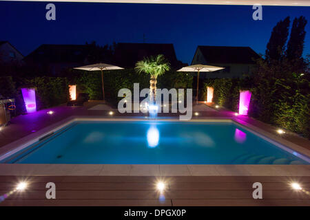 Private garden with pool and terrace and palm with show lighting at night in summer, Germany, Europe - August 2013.