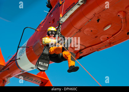 US Coast Guard Petty Officer 3rd Class Andrew Wilson, a rescue swimmer with Air Station Houston is lowered to a small boat in Galveston Bay during training January 9, 2014 in Galveston, Texas. Stock Photo