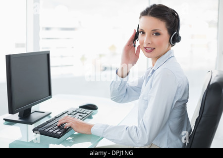 Pretty stylish brunette operator using a computer and answering a call Stock Photo