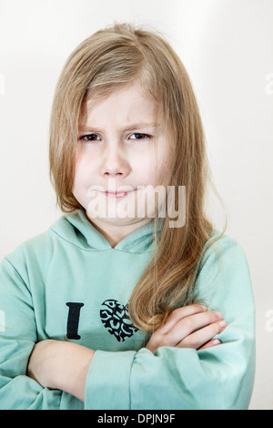 Young girl with an angry look and crossed arms. Head and shoulders portrait Stock Photo