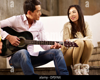 young man playing guitar for girlfriend Stock Photo