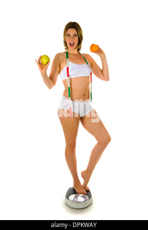 A woman standing on a weight scale with measuring tape and fruit Stock Photo
