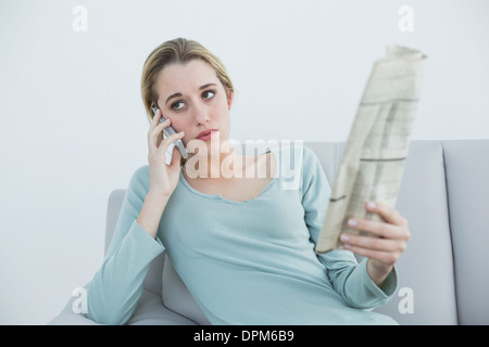 Casual serious woman phoning sitting on couch Stock Photo