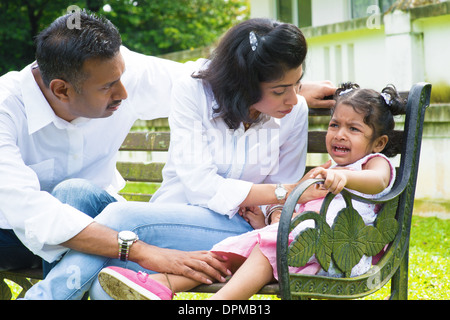 Indian family outdoor. Parents is comforting their crying daughter. Stock Photo