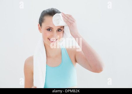 Woman wiping sweat with towel against wall Stock Photo