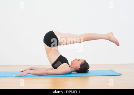 Fit woman doing plough posture in fitness studio Stock Photo