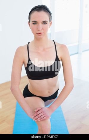 Fit young woman stretching leg in fitness center Stock Photo