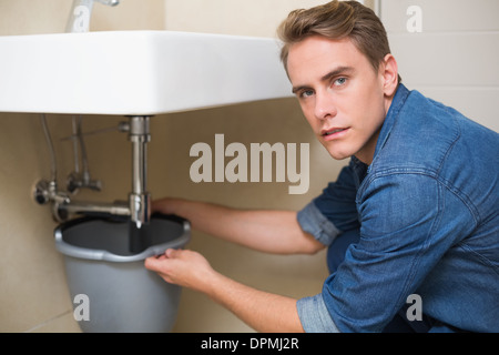Handsome plumber repairing the drain of sink Stock Photo