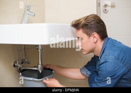 Handsome plumber repairing the drain of sink Stock Photo