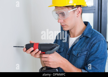 Serious young handyman using a drill Stock Photo