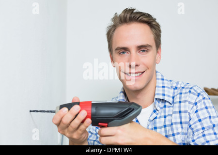 Portrait of handyman using a cordless drill to the wall Stock Photo