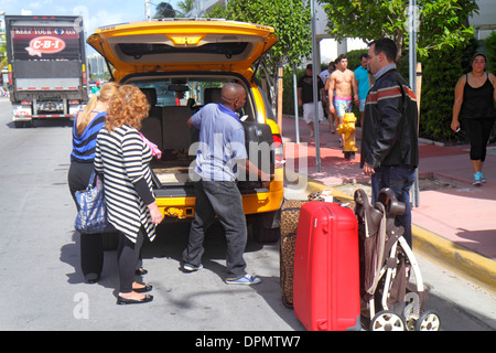 Miami Beach Florida,Ocean Drive,taxi,cab,driver,unloading,luggage,passenger passengers rider riders,service,public transportation,visitors travel trav Stock Photo