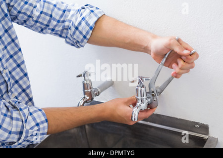 Plumber hand's fixing water tap with pliers Stock Photo