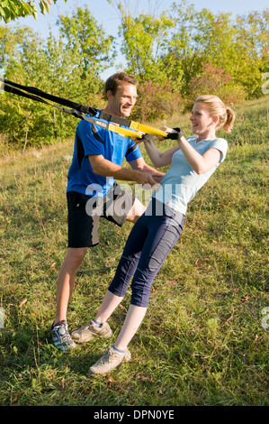 A woman uses suspension rings on a meadow Stock Photo