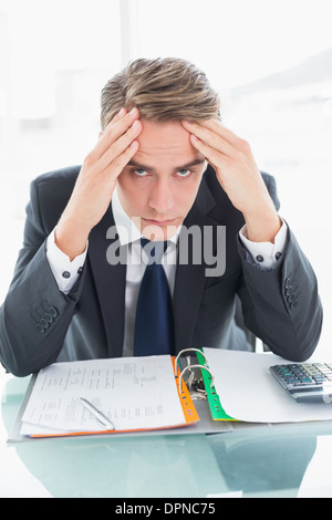 Worried businessman with head in hands at office desk Stock Photo