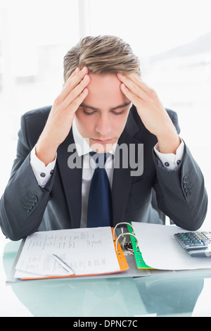 Worried businessman with head in hands at office desk Stock Photo