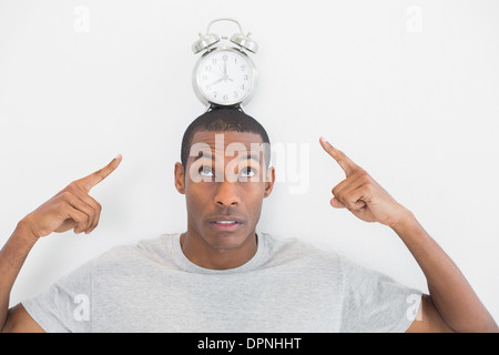 Close up of a man pointing at alarm clock over his head Stock Photo